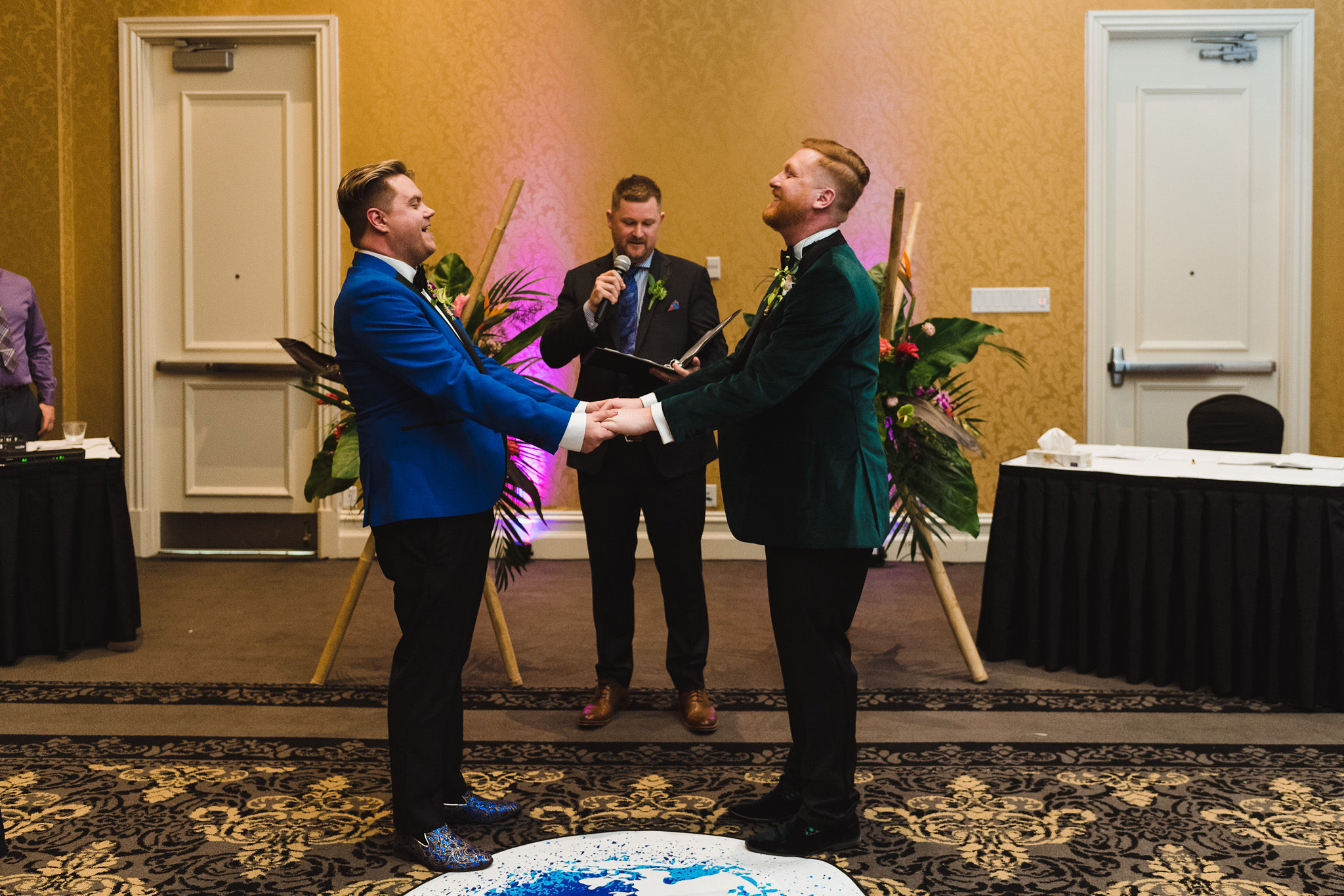 grooms holding hands and laughing during wedding ceremony at the Hilton Fallsview in Niagara Falls