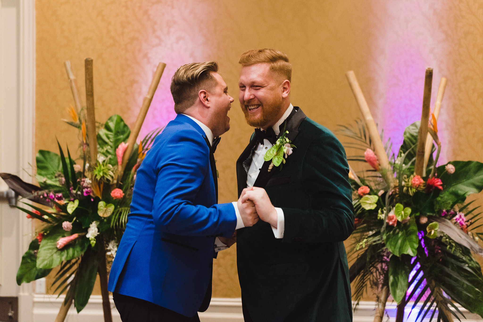 grooms holding hands and laughing hard after their wedding at the Hilton Fallsview in Niagara Falls