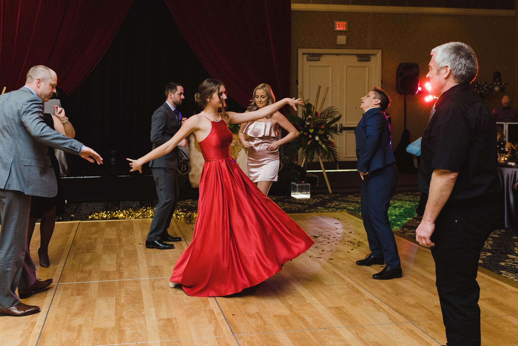 wedding guests dancing and a girl in a red dress twirling during a fun wedding reception at the Hilton Fallsview in Niagara Falls