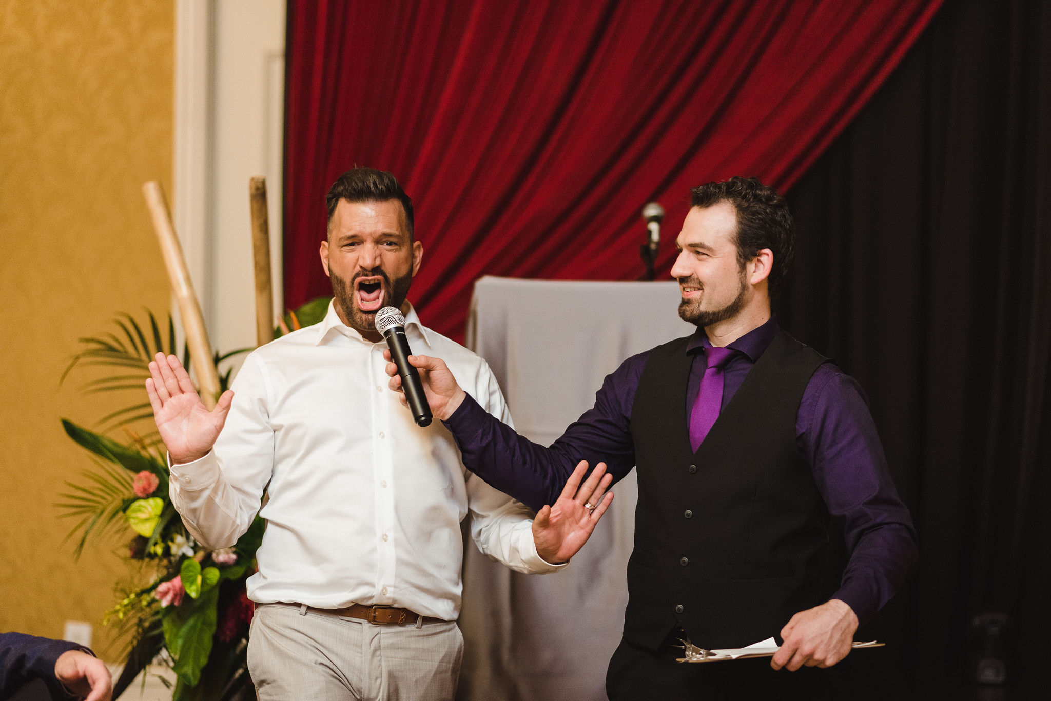 wedding MC holding microphone up to a wedding guest that has his hands up and is yelling during reception at the Hilton Fallsview in Niagara Falls 