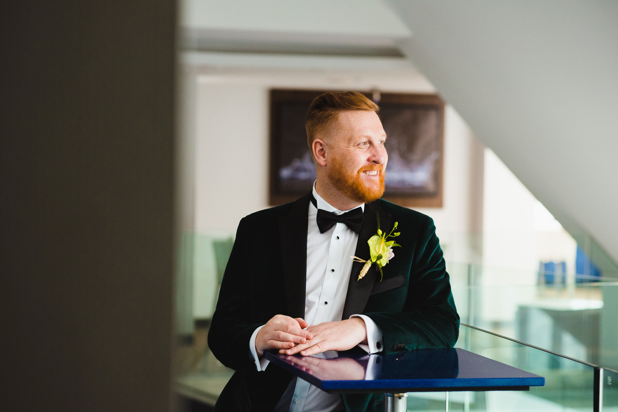 groom in green suit smiling and standing at a bar table before his wedding at the Hilton hotel in Niagara Falls 