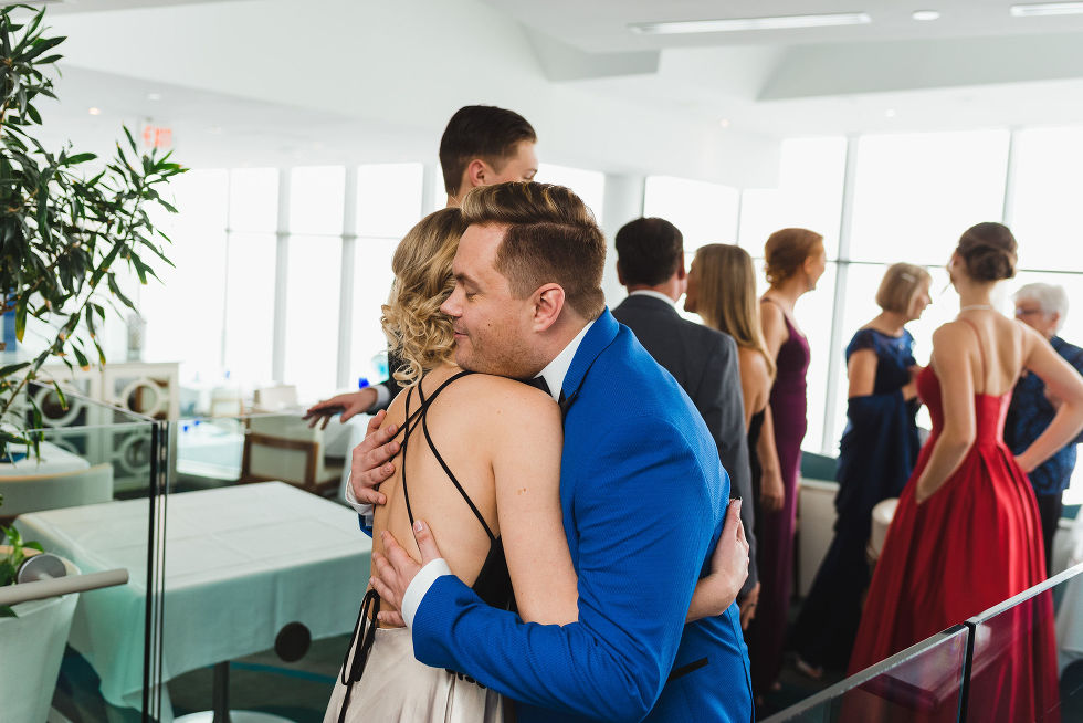 groom in bright blue suit hugging a wedding guest at Hilton Niagara Falls