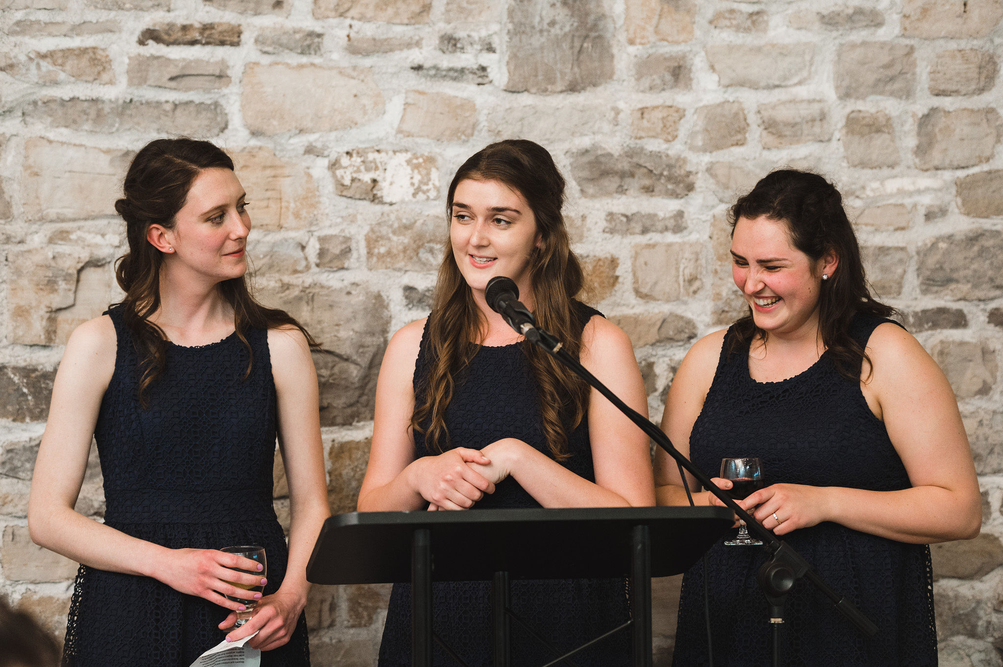 Three bridesmaids reading their speech in front of an old stone wall during a charming southern style wedding at Ruthven National Historic Site near Hamilton