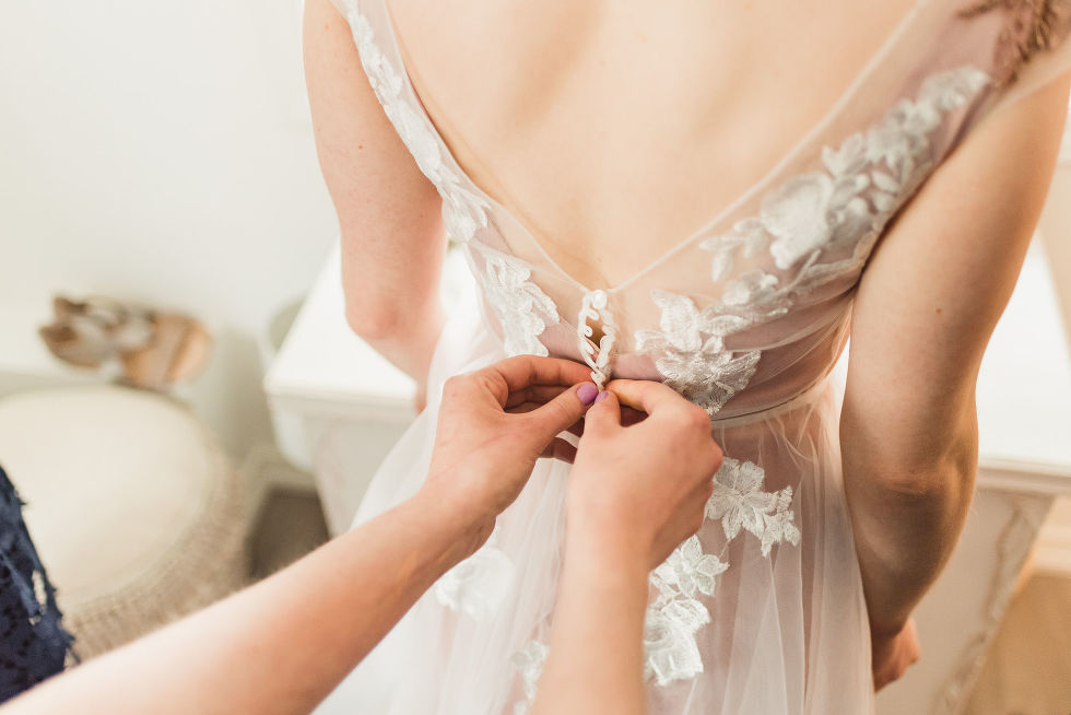 bridesmaids hands doing up the buttons on the back of the brides wedding dress before her charming southern style wedding at Ruthven Park National Historic Site