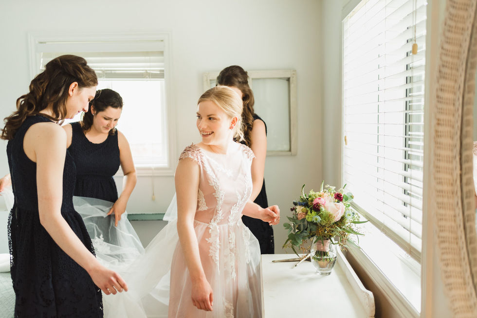 bride smiling as she gets ready with her bridesmaid surrounding her before her charming southern style wedding at Ruthven Park National Historic Site