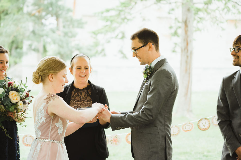 bride placing ring on her grooms hand during their charming southern style wedding ceremony at Ruthven national historic site 