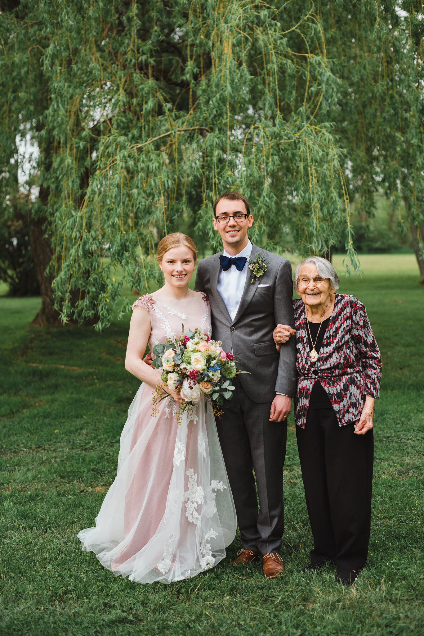 bride and groom stand with the grandmother underneath a willow tree during their southern style wedding at Ruthven National Historic Site near Hamilton