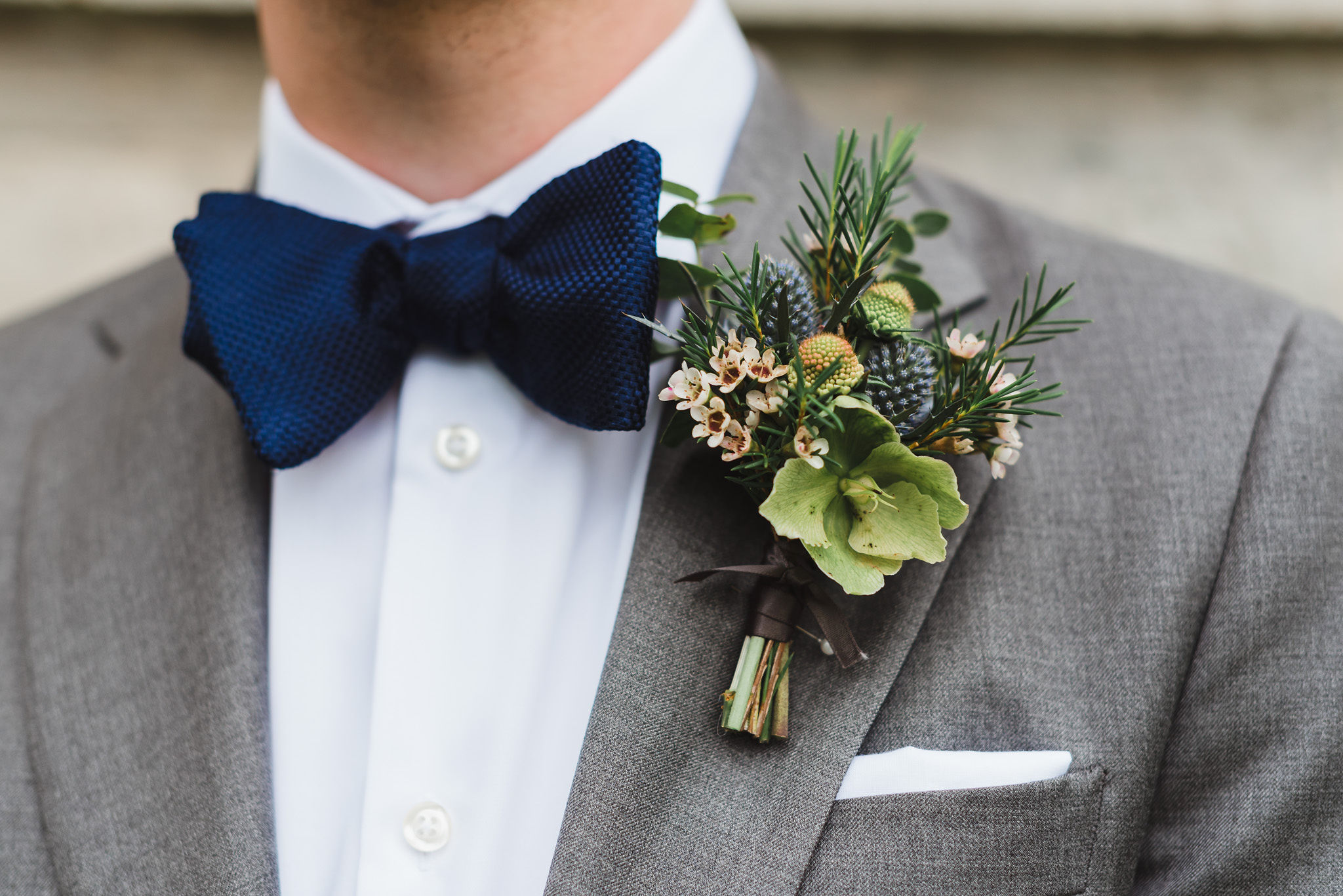 groom in a grey suit with a blue bowtie and a boutonniere during his charming southern style wedding at Ruthven National Historic Site 
