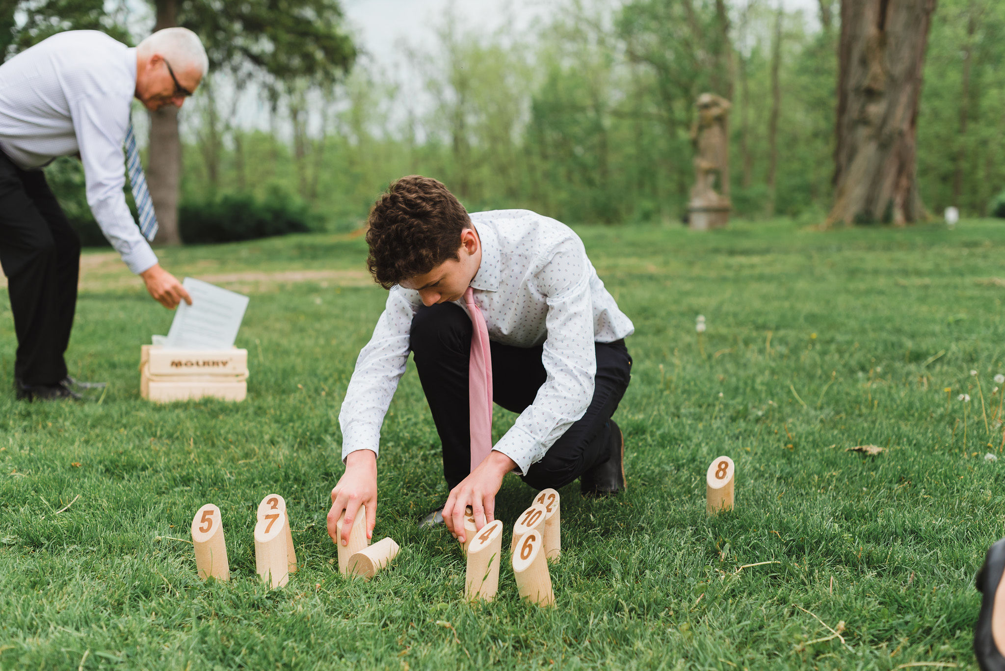 A couple of wedding guests setting up a game with wooden pegs with numbers on them on the lawn of the Ruthven National Historic Site during a charming southern style wedding near Hamilton