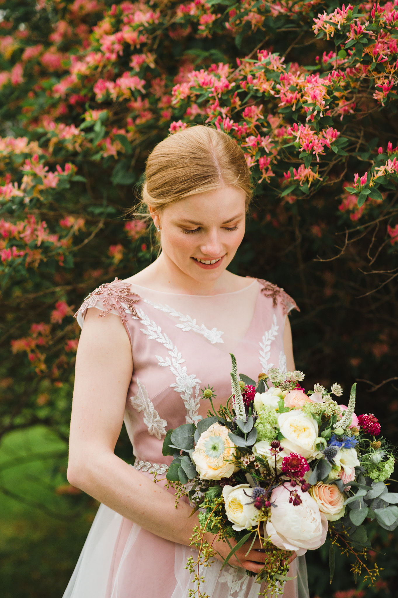 bride standing in front of a wall of colourful flowers holding a bouquet during her charming southern style wedding at Ruthven National Historic Site near Hamilton
