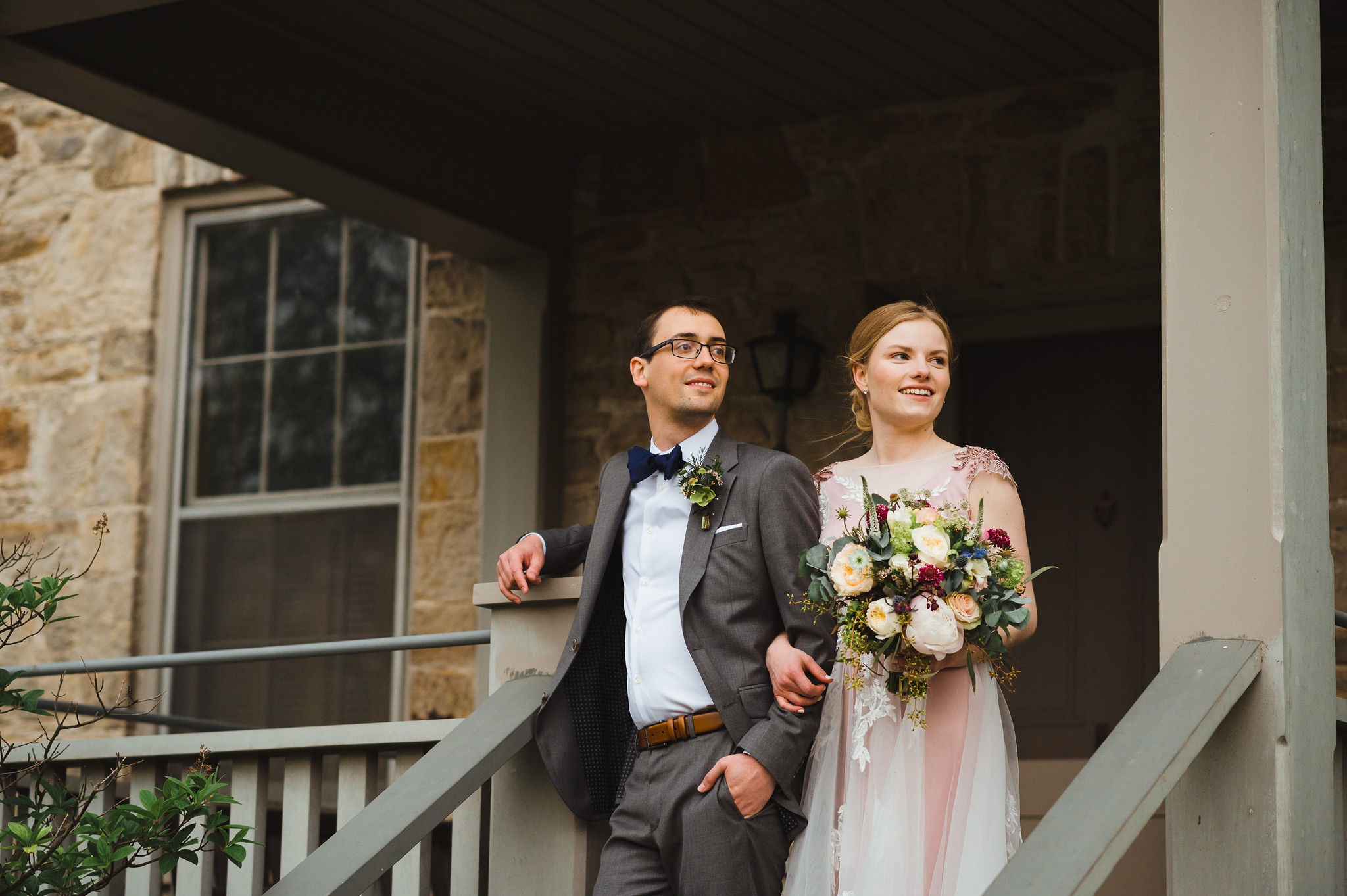 bride holding a colourful floral bouquet and her other arm linked with her grooms during their charming southern style wedding at Ruthven National Historic Site near Hamilton