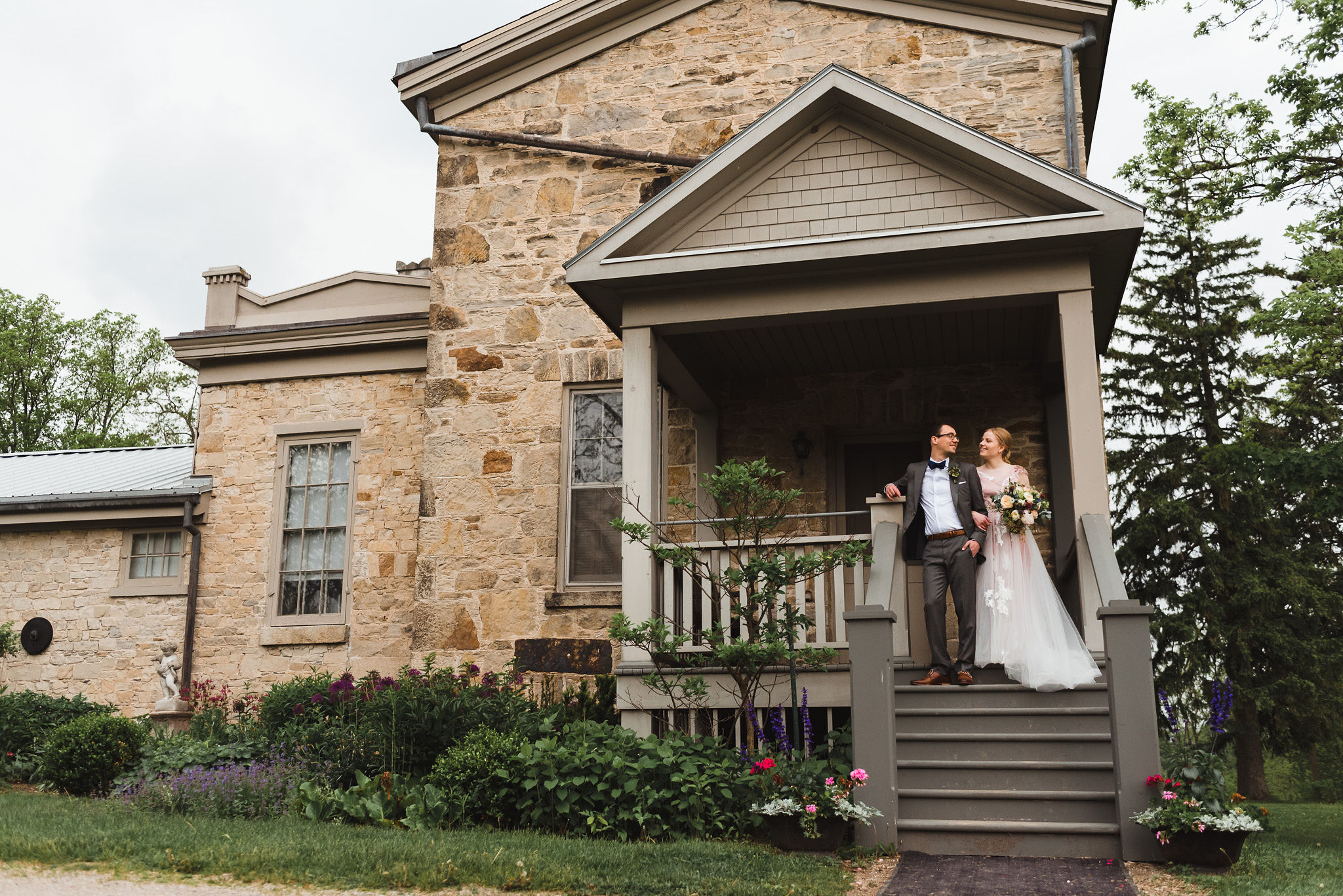 bride holding a colourful bouquet and her other arm linked with her grooms during their charming southern style wedding at Ruthven National Historic Site near Hamilton