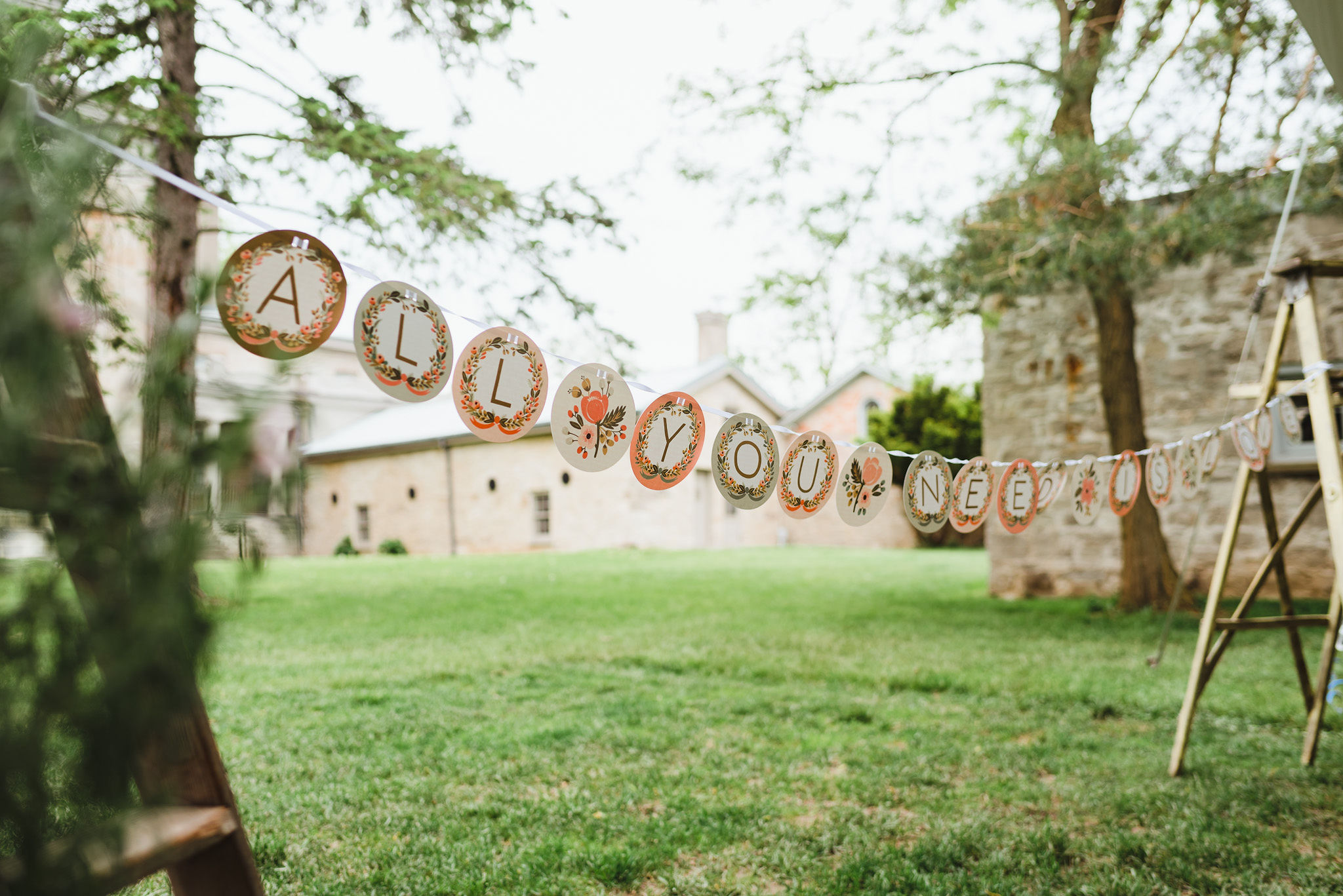 Paper circles strung up saying "ALL YOU NEED IS LOVE" outside Ruthven Park National Historic Site during a charming southern style wedding