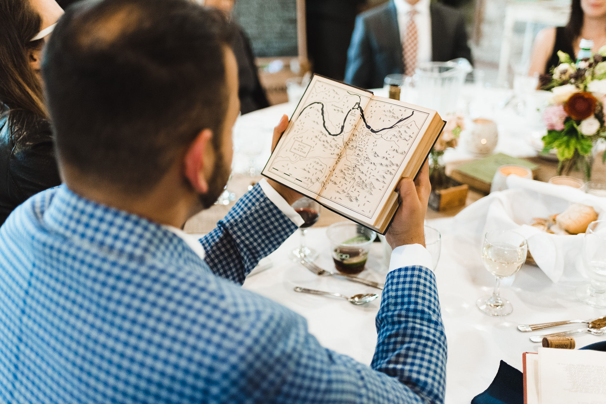 a wedding guest seated at his table and opening a book to look inside during a charming southern style wedding at Ruthven national historic site