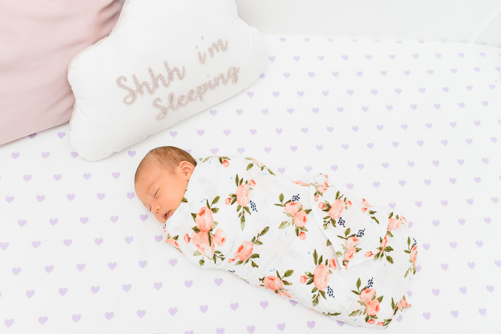 A newborn baby swaddled in a floral blanket resting in their crib Toronto family photos