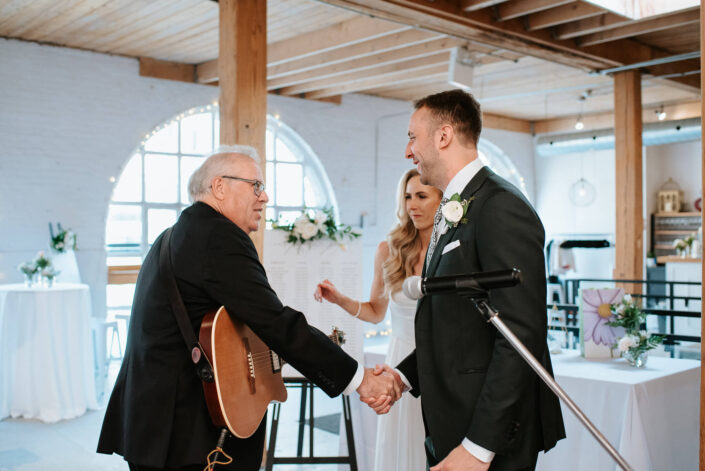 groom shaking hands with performer